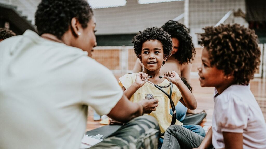 Drei Kinder sitzen im Kreis und sprechen miteinander im Freien.