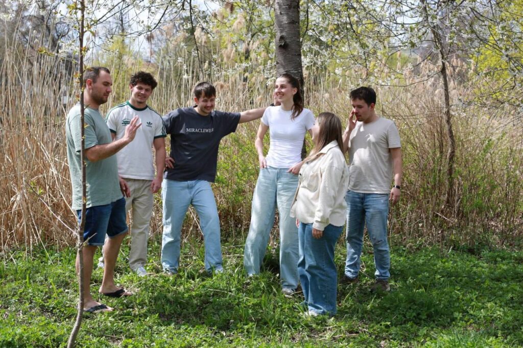 Gruppe von jungen Menschen beim Gebet im Grünen, umgeben von Bäumen und Natur, bei einer Gemeinschaftsveranstaltung in der Nähe des Schwarzwalds und Bodensees.