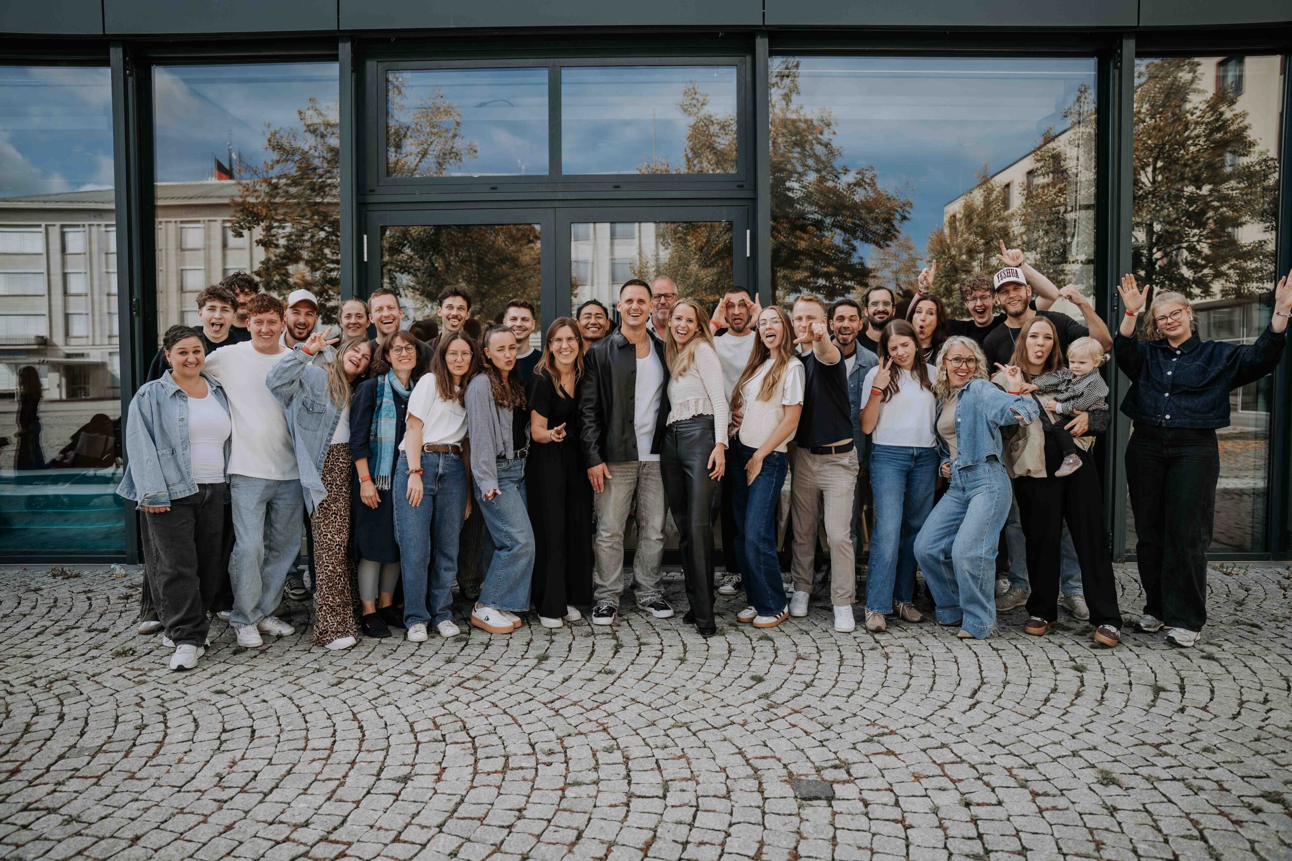 Gruppenfoto der ICF Schwarzwald Bodensee Gemeinde vor einem modernen Gebäude, das Gemeinschaft und Glauben in der Region repräsentiert.