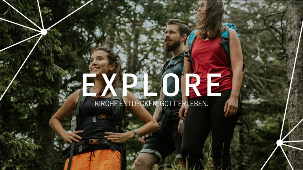 Drei Menschen wandern in einem Wald, lachen und schauen in verschiedene Richtungen.