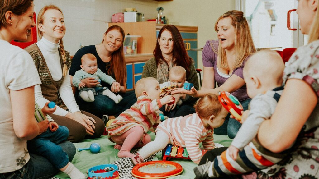 Mehrere Erwachsene und Babys in einem Raum, spielen und interagieren.