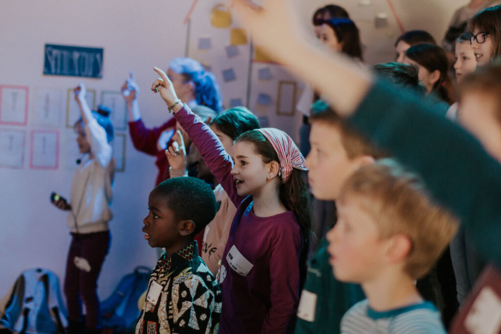 Kinder in einer Gruppe heben die Hände während einer Aktivität im Kids Church.
