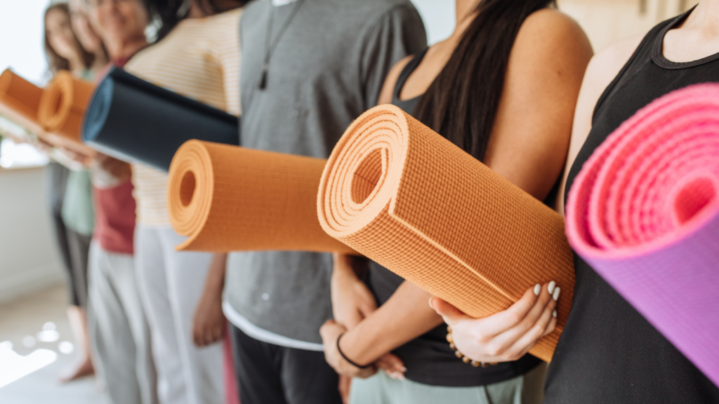 Menschen stehen in einer Reihe, halten Yoga-Matten in verschiedenen Farben.