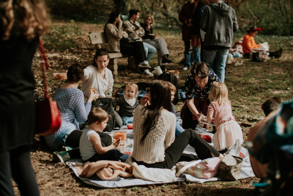 Gruppe von Erwachsenen und Kindern beim Picknick im Park.