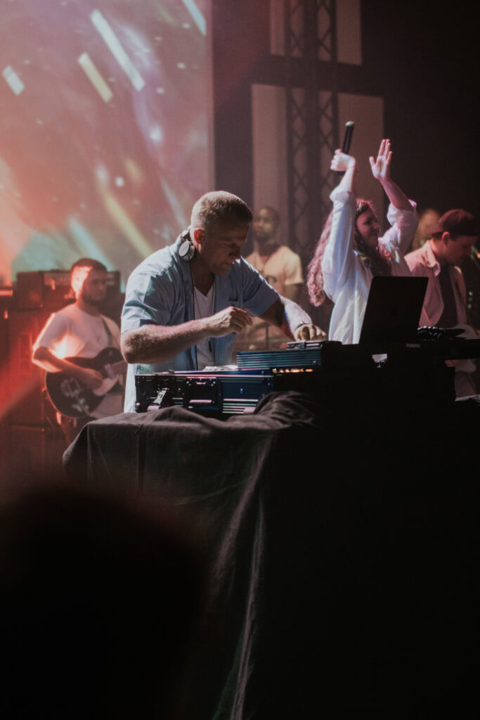 DJ mit Kopfhörern spielt an Turntable bei Konzert.