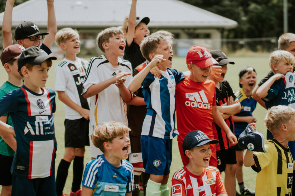 Junge Kinder jubeln und feiern auf einem Sportfeld.