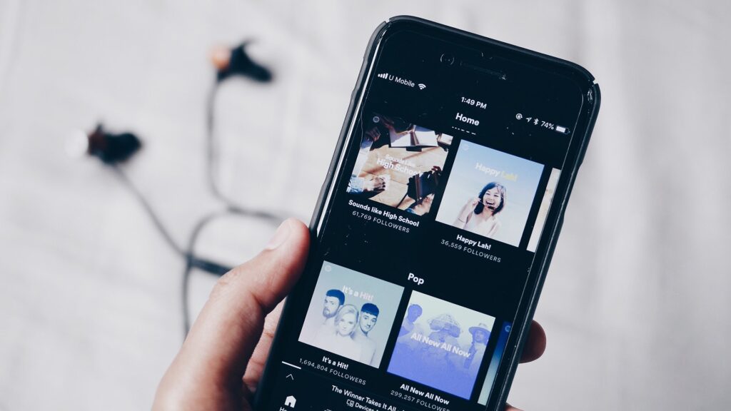 Hand hält Smartphone mit Musik-Streaming-App auf dem Bildschirm.