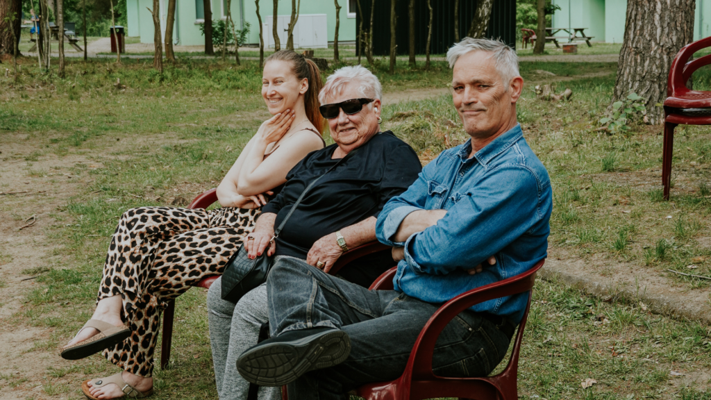 Drei Menschen sitzen auf Bänken im Park, lachen und unterhalten sich.