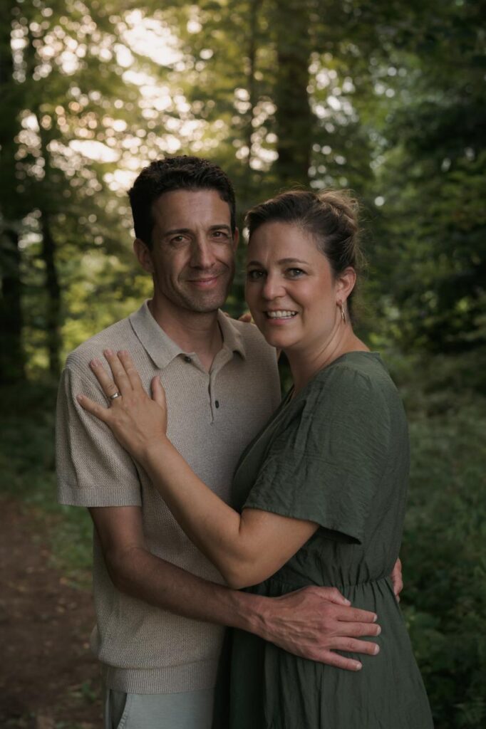 Ein Mann und eine Frau umarmen sich im Wald bei Sonnenuntergang.