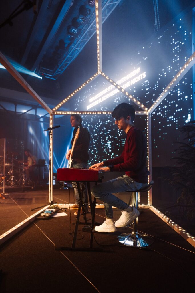 Junger Musiker spielt Keyboard auf einer Bühne mit LED-Hintergrund.