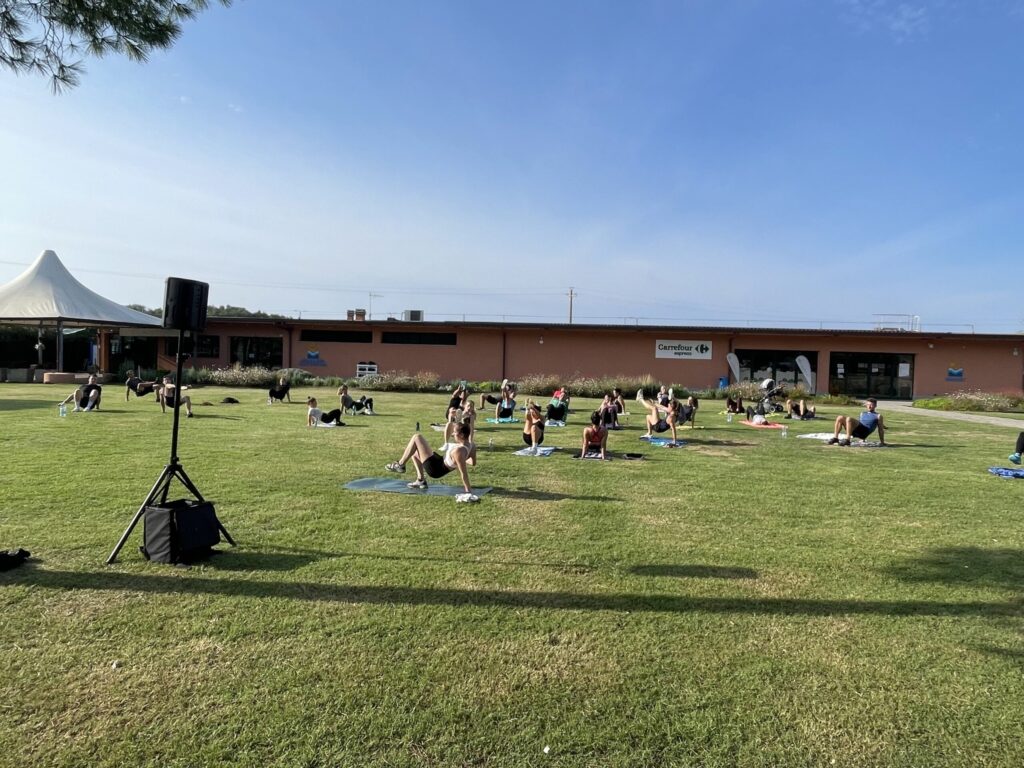 Menschen beim Yoga im Freien auf einer Wiese bei Sonnenschein.