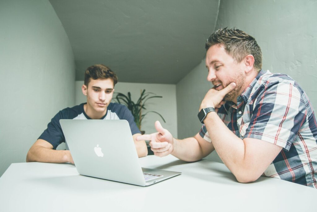 Lehrer und Schüler bei Laptop-Training, Lehrer zeigt auf den Bildschirm.