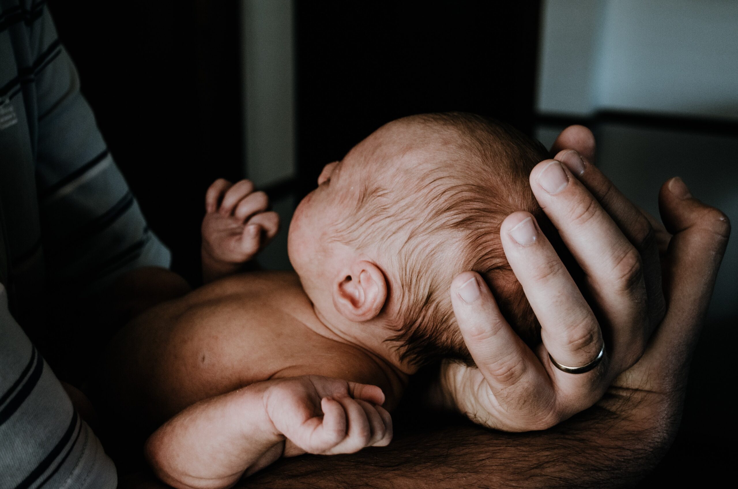 Nahaufnahme eines Babys, das auf einem Arm liegt, Kopf an der Schulter.