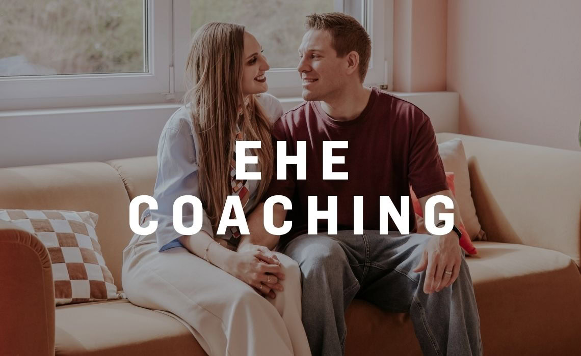 Ehe Coaching, ein Paar sitzt auf einer Couch und spricht miteinander.