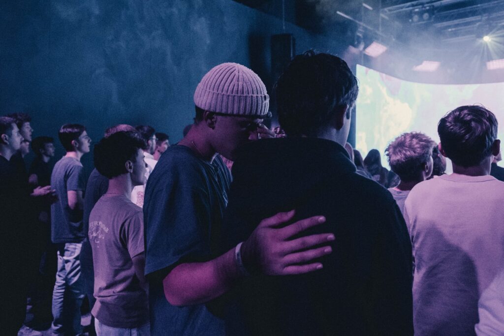 Group of young people at a concert, some hugging each other.